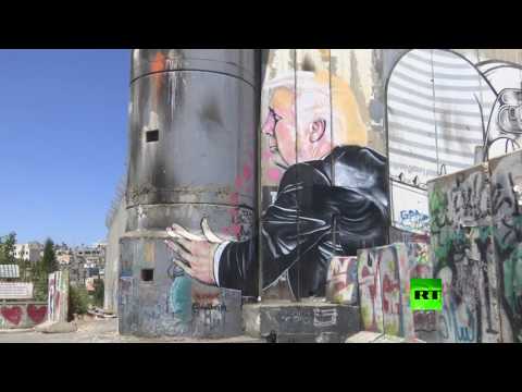 شاهد ترامب يعانق الجدار الإسرائيلي في لوحة فنية قرب بيت لحم