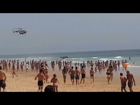 شاهد زورقٌ للمهاجرين المغاربة يرسو على شاطئ إسباني وسط آلاف السياح